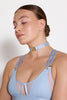Bordelle Vero light dusty blue wireless bralette. Opaque triangles cover sheer mesh bandeau with center cutout. Two adjustable satin elastic shoulder straps on each side. Front view on model in matching collar.