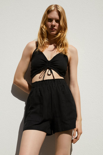 Else Ponza cotton ruched front crop top in black, shown on model with matching shorts. The top features a v-neckline and halter style straps. Front view.