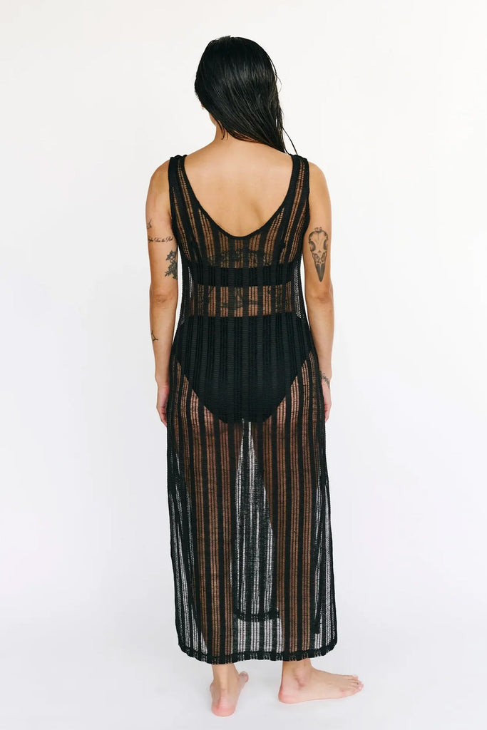 Else St. Tropez black knit swim coverup dress. The knit features a sheer striped pattern. The sleeveless dress has a scoop neck and side slits, with an ankle length hemline. Back view shown on model wearing a two piece black swimsuit underneath.