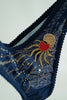 Close up view of Eclipse Thong by Love & Swans. Dark blue mesh is embroidered and beaded with a sun and moon crossing paths, rays emitting from both and the latin words for "love conquers all." 