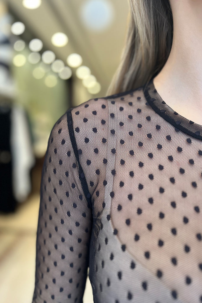 Close up detail of the crew neck and dot pattern on the sheer black polka dot Coucou Lola Natasha Tea Dress by Only Hearts, shown on model.