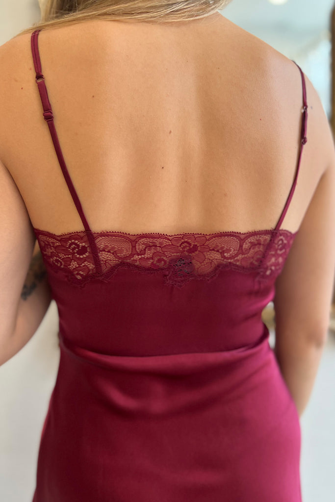 Detail of Only Hearts Silk Charmeuse Mini Slip in burgundy Dahlia adjustable shoulder straps and lace trim, back view on model.