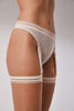 Opaak Lil leg strap garter in light beige (bleached sand), attached to matching Anou sheer mesh thong, side/front view, on model