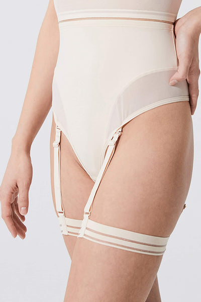 Opaak Lil leg strap garter in light beige (bleached sand), side/front view, on model
