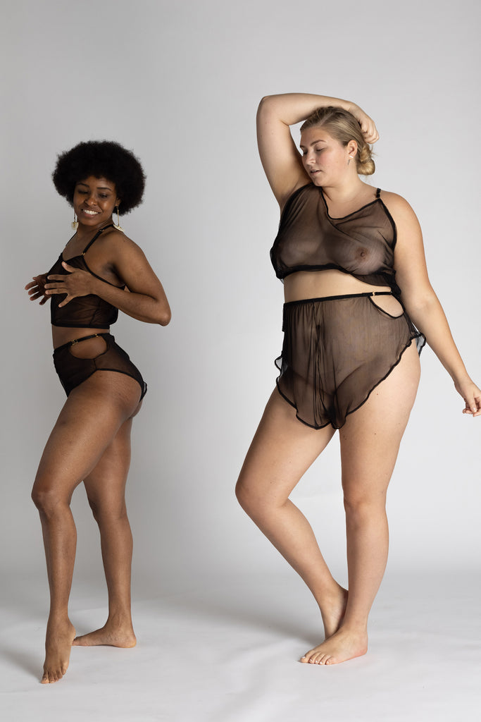 Sheer black Eartha Tap pant shorts with ruffled bottom by Adrina Dietra. The shorts are shown on 2 different models of different sizes illustrating how the tap pants can fit loosely or tightly according to preference and shape. Front and side view shows the models engaging in dancing motions.