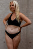 Black Canggu low rise bikini swim bottom by Copenhagen Cartel. Front view on model with matching Bukit swim top.