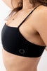 Sanur swim top in Nero with thin spaghetti straps. Side view on model shows small Copenhagen Cartel logo.