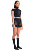 DSTM Innsai Brief in black, shown on model with the matching top. Shorts feature opaque panels with sheer inserts at the mid front and side hip/legs. The briefs are like shorts, with the hemline on the upper thigh. Front/side view.