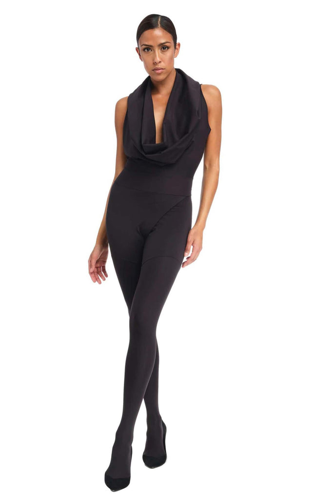 Footed, sleeveless black shadow suit by DSTM with cowl neckline. Front view on model who is taking a step forward in matching heels.