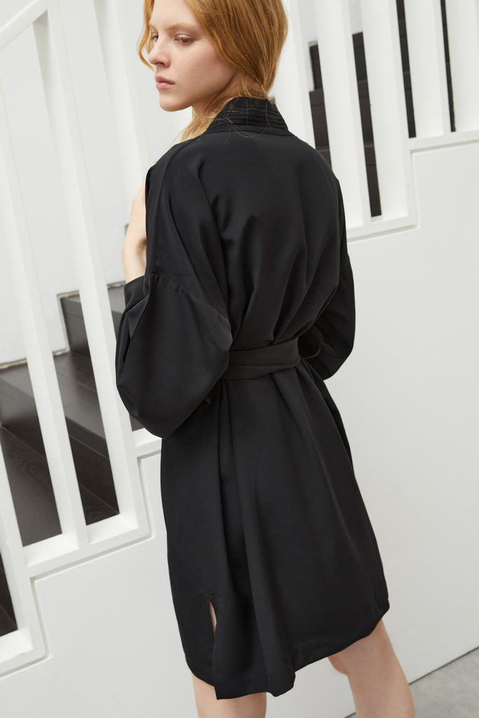 Else Diana black silk robe shown on model, back view. The robe features a pleated detail around the collar and is shown tied at waist. The side slits and drop shoulders are also shown here. 