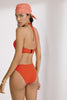 Poppy red-orange Penelope bandeau bikini top with thin halter strap by Else. Back view on model shows black clasp at the mid back.