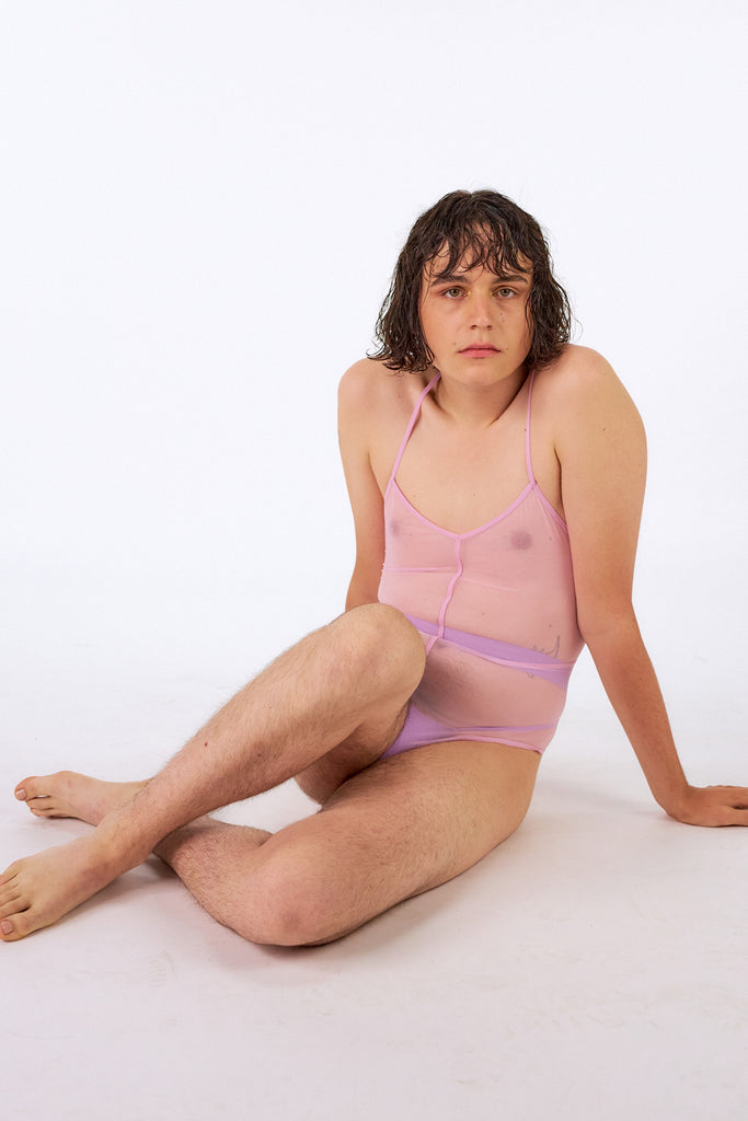 La fille d'o Above Reversible tulle rose pink bodysuit with skinny sporty straps and seams. Front view on seated model.