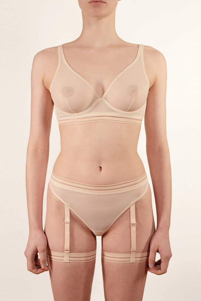 Opaak Lil leg strap garter in light beige (bleached sand), attached to matching Anou sheer mesh thong, front view, on model