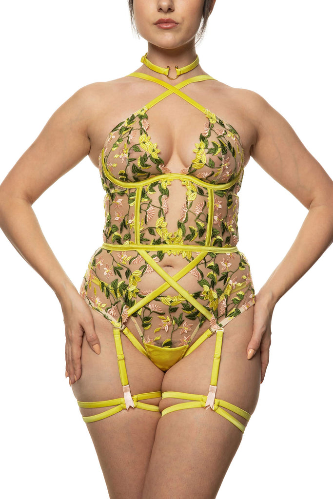 Studio Pia chartreuse Liana basque with spring floral embroidery, gold plated hardware, and straps that criss cross at the chest and stomach. Front view on model with matching strap thong.