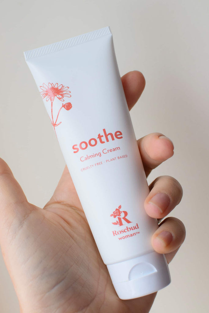 Rosebud Woman Soothe calming cream in a person's hand, on beige background
