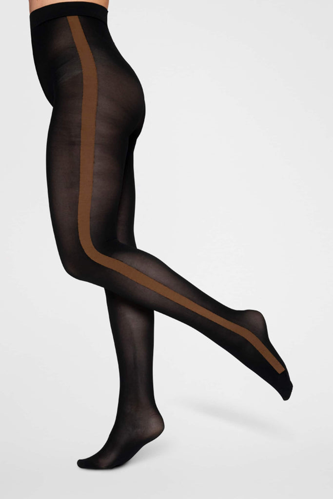 Black semi-opaque pantyhose with brown side stripe from waist to toe from Swedish stockings. On model from waist down in front of plain white background.