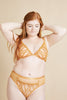 You Are Important plunge bra in yellow-orange mustard mesh and swirling embroidery. The bra is plunge style with triangle shaped cups. Shown on model, front view close up, with matching briefs.