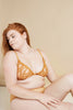 You Are Important plunge bra in yellow-orange mustard mesh and swirling embroidery. The bra is plunge style with triangle shaped cups. Shown on model, front view, with matching briefs.