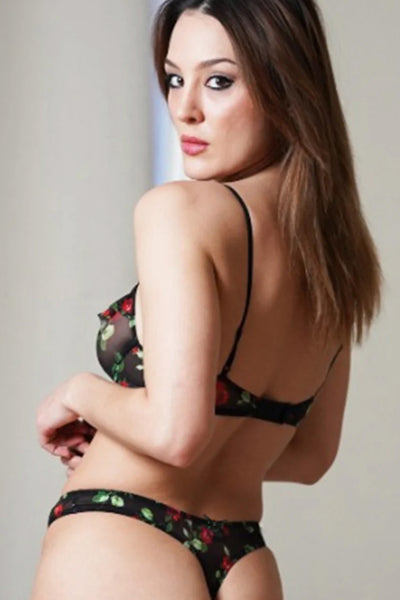 Only Hearts Betsey Rose vintage thong in black mesh with green and red rose print, back view on model. Image shows a tiny bow at the back of the thong and high cut leg/mid rise waist design. Model is wearing matching bra. 